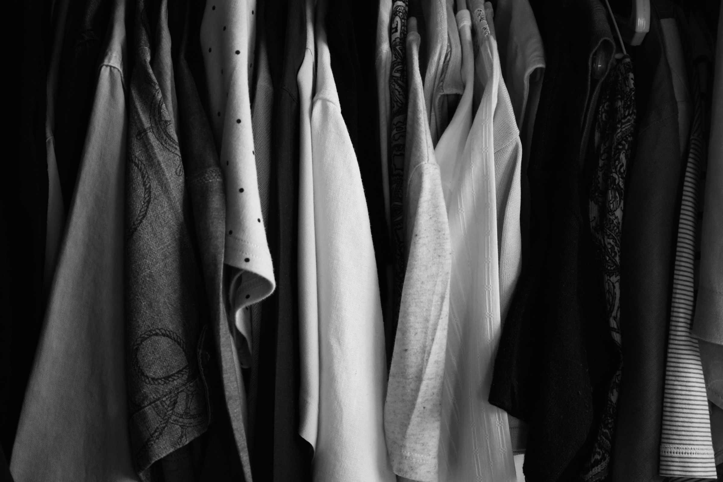 Black and white image of shirts hung in a closet before being packed in a box to move